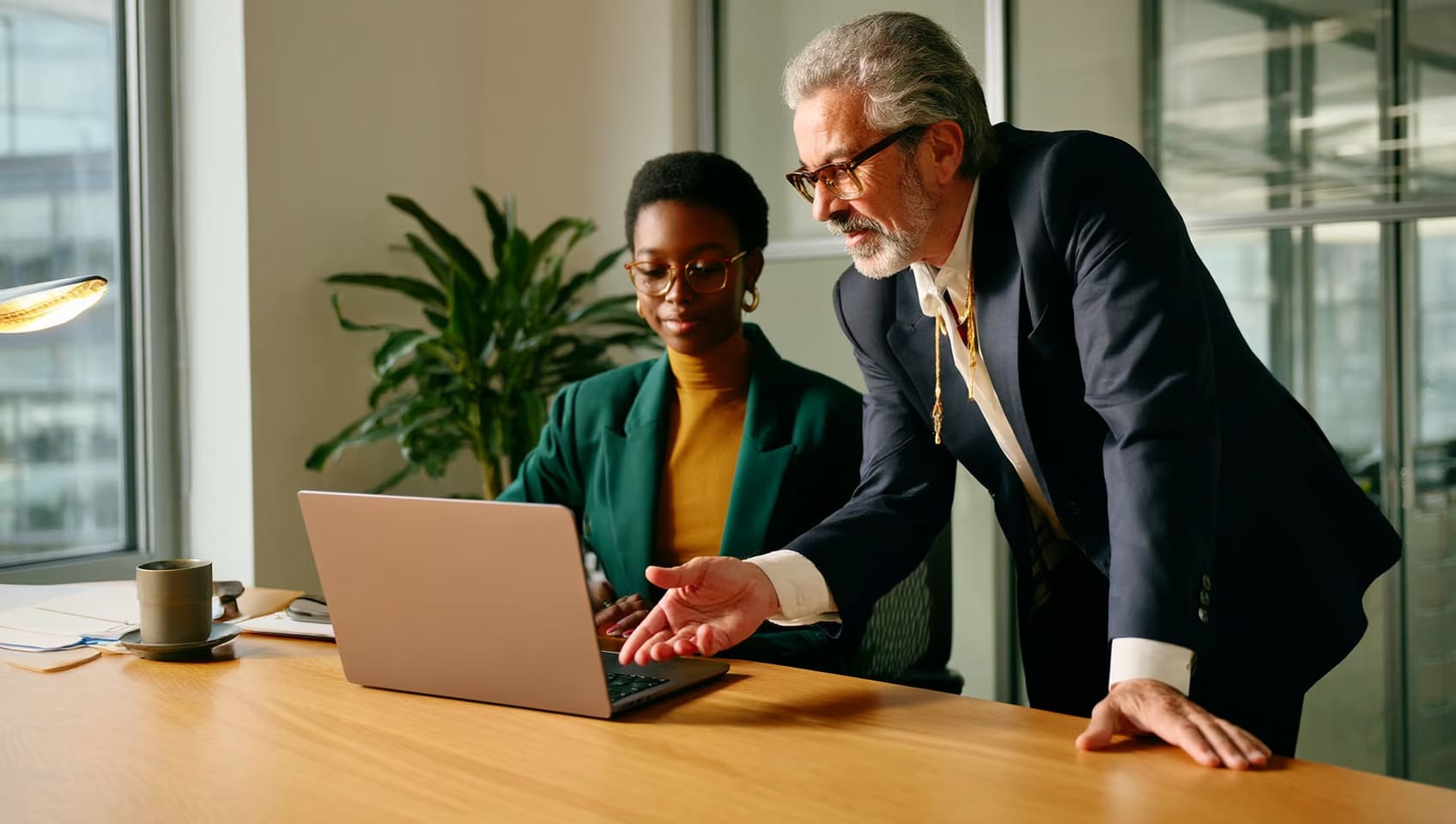 A senior JULY leader mentoring a younger colleague over a laptop in a warm Vancouver office